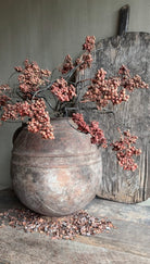 Kunstboeket ligustrum met dusty red bessentakken en takkenbos in een oude stenen pot